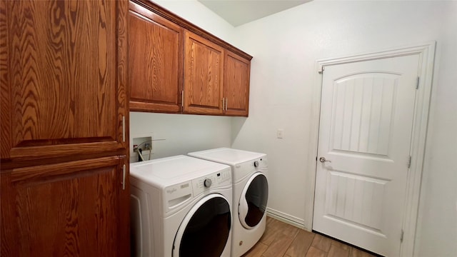 clothes washing area featuring cabinets, separate washer and dryer, and light hardwood / wood-style floors