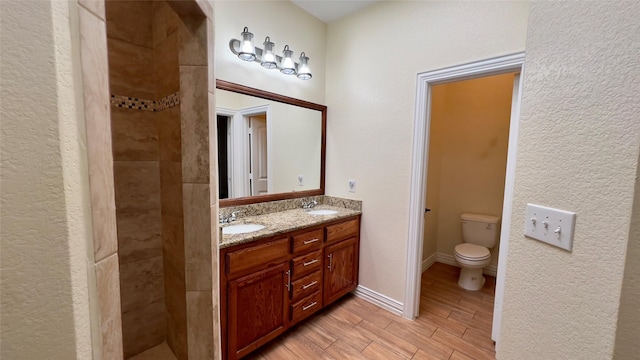 bathroom with tiled shower, vanity, and toilet