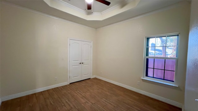 spare room with hardwood / wood-style flooring, ornamental molding, ceiling fan, and a tray ceiling