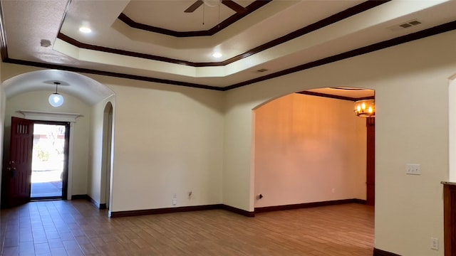 entrance foyer with crown molding, hardwood / wood-style floors, a tray ceiling, and ceiling fan