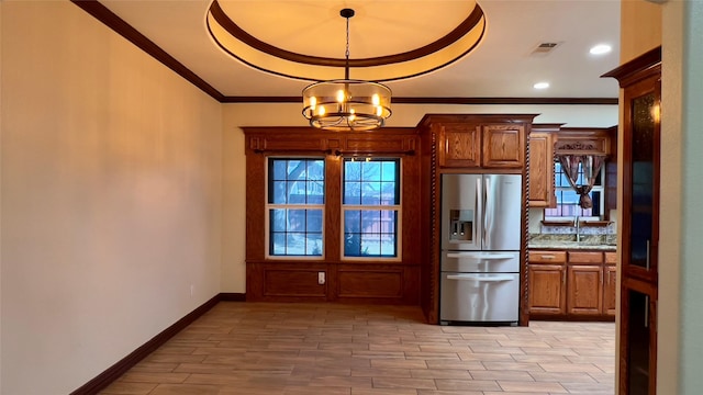 kitchen with an inviting chandelier, light stone counters, ornamental molding, stainless steel fridge with ice dispenser, and decorative light fixtures