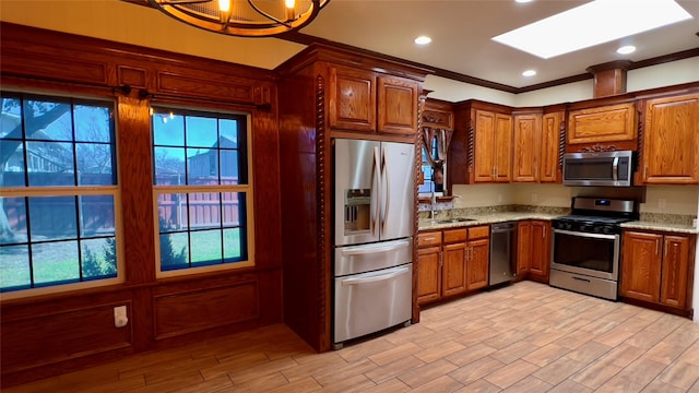 kitchen featuring stainless steel appliances, light stone countertops, sink, and light wood-type flooring