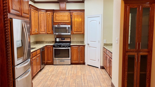 kitchen featuring light stone countertops, stainless steel appliances, and light wood-type flooring