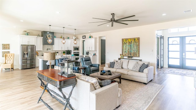 living room with ceiling fan, light hardwood / wood-style floors, and french doors