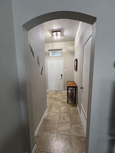 hall featuring light tile patterned floors and a textured ceiling