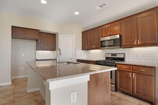 kitchen featuring a kitchen island with sink, sink, light stone counters, and stainless steel appliances