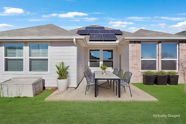 rear view of property featuring a patio, a lawn, and solar panels