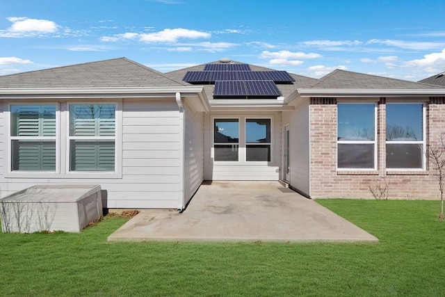 back of house featuring a yard, a patio, and solar panels