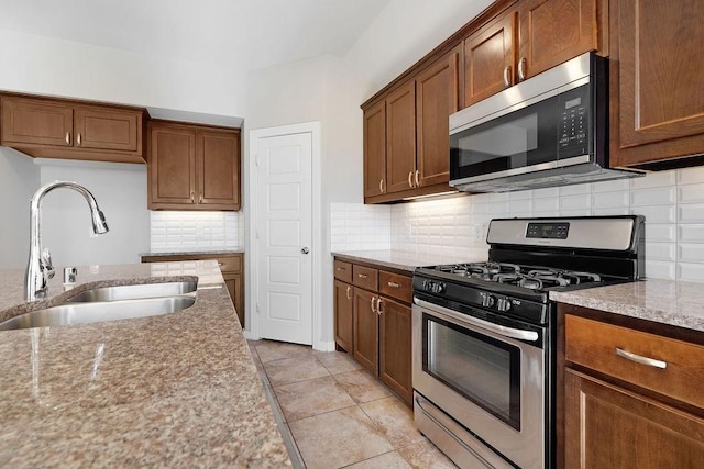 kitchen featuring light tile patterned flooring, sink, tasteful backsplash, stainless steel appliances, and light stone countertops