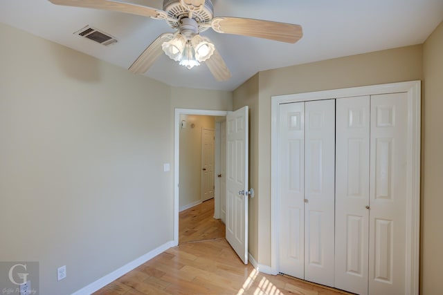 unfurnished bedroom with ceiling fan, a closet, and light wood-type flooring