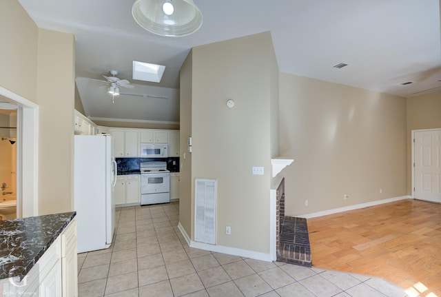 kitchen with light tile patterned floors, white appliances, ceiling fan, white cabinets, and a brick fireplace