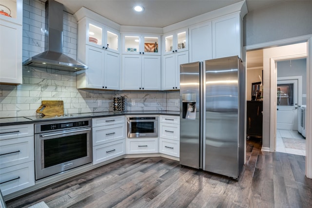 kitchen featuring tasteful backsplash, wall chimney range hood, stainless steel appliances, and white cabinets