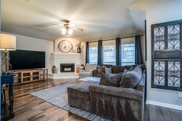 living room featuring dark hardwood / wood-style flooring, a brick fireplace, and ceiling fan