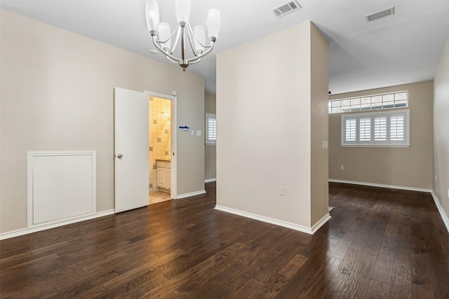 spare room featuring dark hardwood / wood-style floors and a notable chandelier