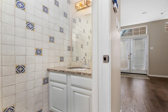 bathroom featuring tile walls, hardwood / wood-style floors, vanity, and french doors