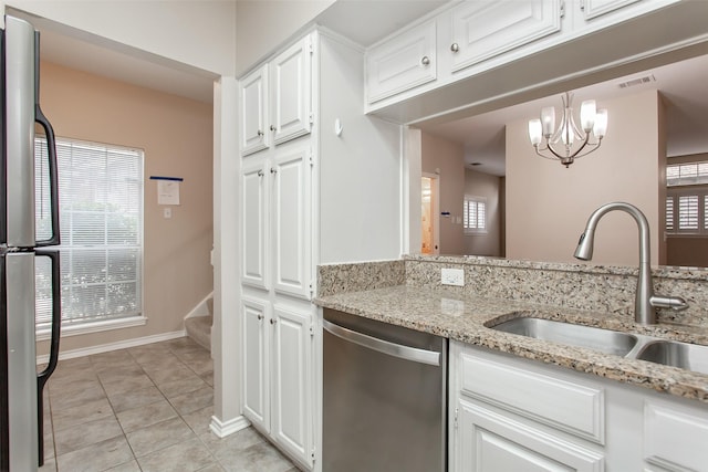 kitchen featuring sink, appliances with stainless steel finishes, light stone countertops, white cabinets, and decorative light fixtures