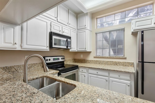 kitchen featuring light stone counters, appliances with stainless steel finishes, sink, and white cabinets