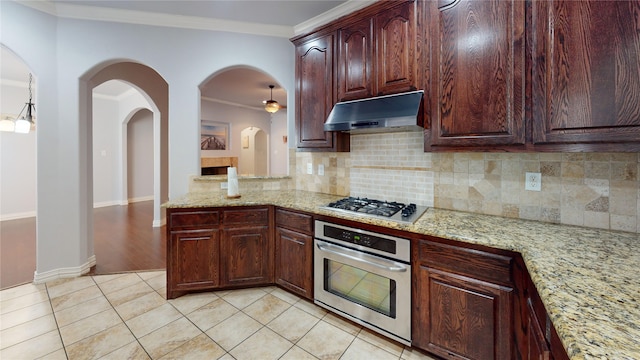 kitchen featuring light tile patterned floors, crown molding, stainless steel appliances, light stone countertops, and decorative backsplash