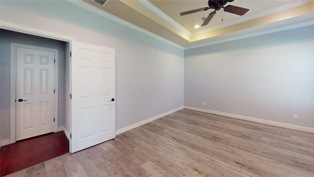 spare room featuring ornamental molding, ceiling fan, light wood-type flooring, and a tray ceiling