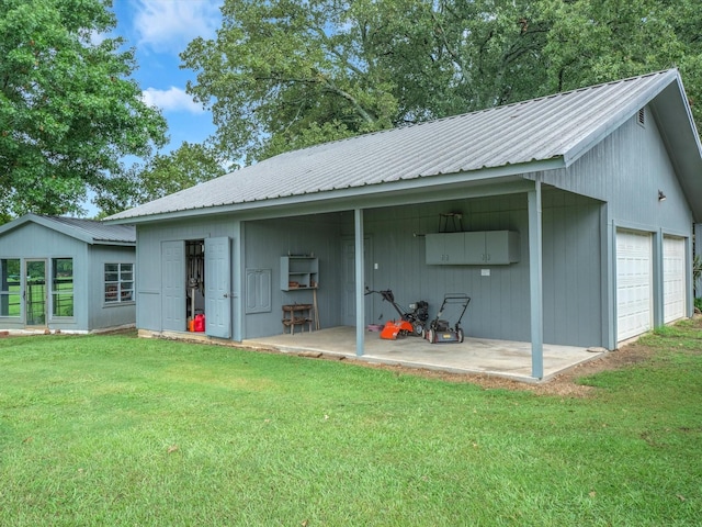 rear view of house with a garage, an outdoor structure, and a lawn