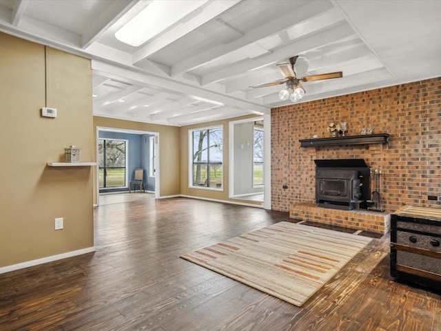 living room with a wood stove, beamed ceiling, ceiling fan, brick wall, and hardwood / wood-style floors