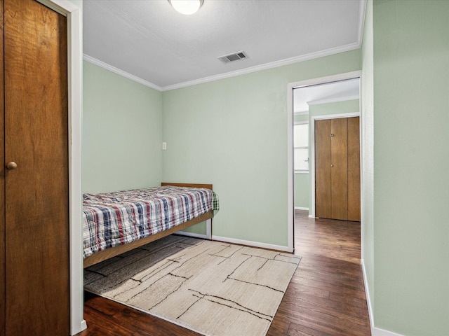 bedroom with ornamental molding and dark hardwood / wood-style floors