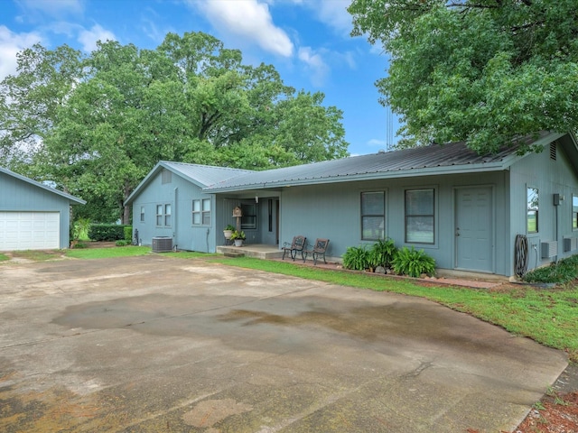 ranch-style house featuring a garage, an outdoor structure, central AC unit, and covered porch