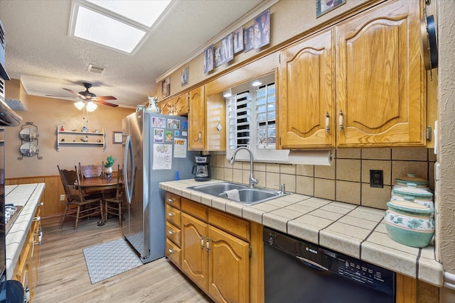 kitchen featuring dishwasher, sink, tile counters, and stainless steel fridge