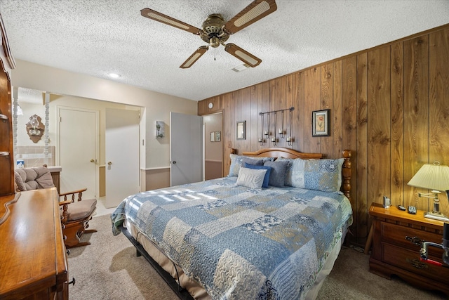 bedroom featuring ceiling fan, carpet, wooden walls, and a textured ceiling