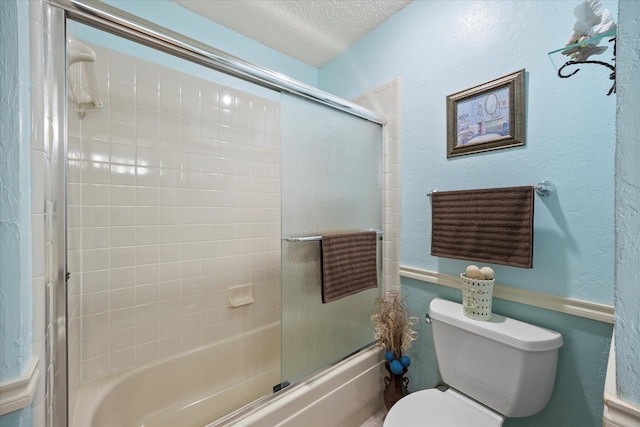 bathroom featuring toilet, bath / shower combo with glass door, and a textured ceiling