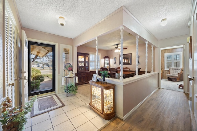 foyer entrance featuring crown molding, ceiling fan, decorative columns, light hardwood / wood-style floors, and a textured ceiling