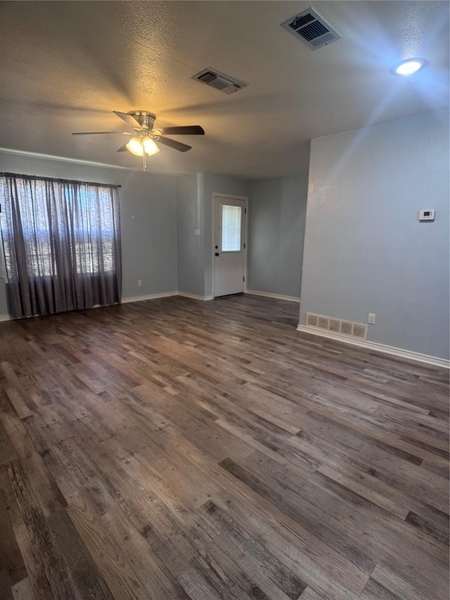 spare room featuring dark wood-type flooring, ceiling fan, and a textured ceiling