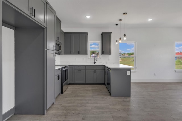 kitchen featuring pendant lighting, stainless steel appliances, kitchen peninsula, and gray cabinetry