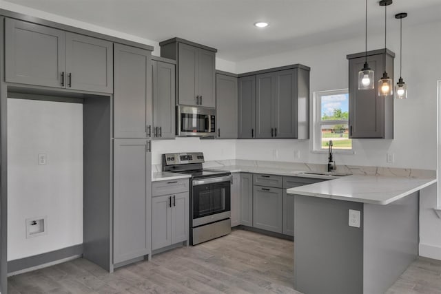 kitchen featuring sink, gray cabinetry, hanging light fixtures, appliances with stainless steel finishes, and kitchen peninsula