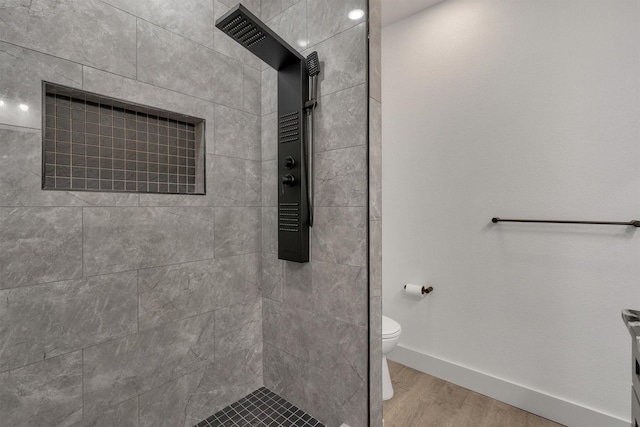 bathroom with tiled shower, wood-type flooring, and toilet