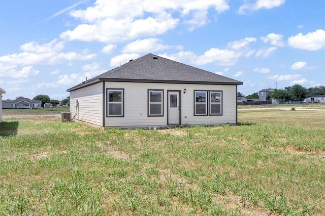 rear view of house with cooling unit and a yard