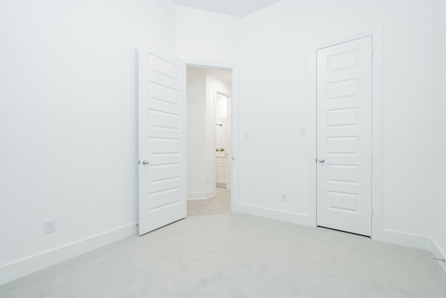 unfurnished bedroom featuring light colored carpet and baseboards