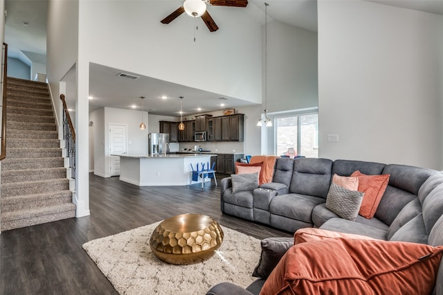 living room featuring dark hardwood / wood-style floors, ceiling fan with notable chandelier, and high vaulted ceiling