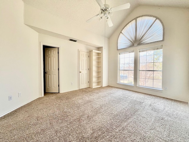 unfurnished bedroom featuring ceiling fan, vaulted ceiling, a textured ceiling, and carpet