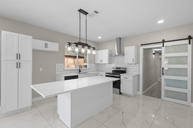 kitchen featuring wall chimney range hood, stainless steel electric range, white cabinetry, a center island, and a barn door