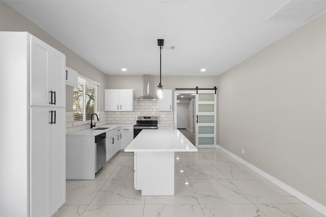 kitchen featuring wall chimney exhaust hood, sink, appliances with stainless steel finishes, pendant lighting, and a barn door