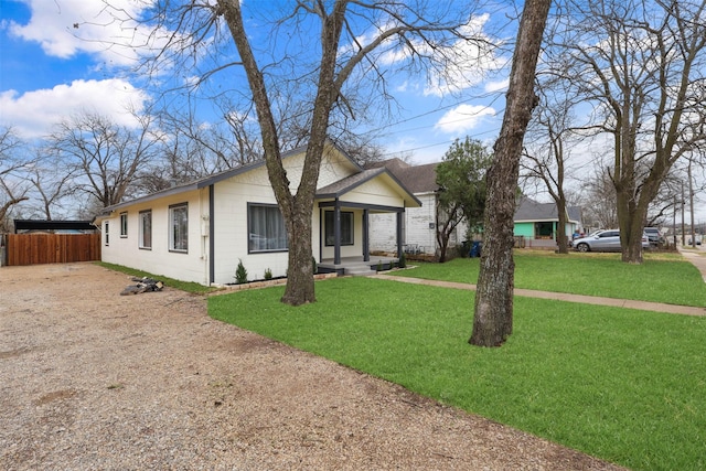 view of front of property with driveway, concrete block siding, a front lawn, and fence