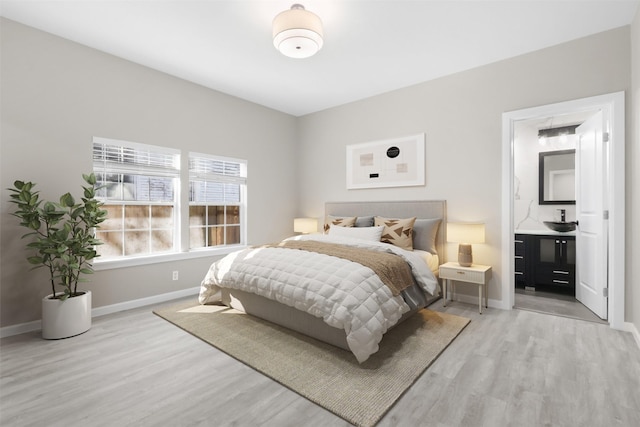 bedroom with ensuite bathroom and light hardwood / wood-style floors