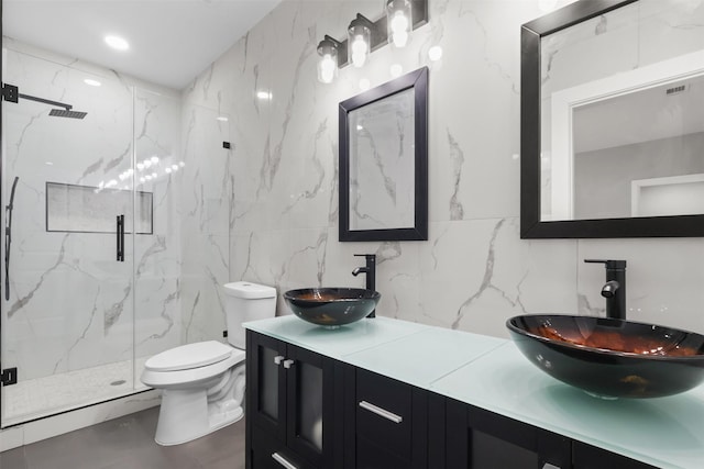 bathroom featuring tasteful backsplash, tile walls, vanity, toilet, and a shower with door