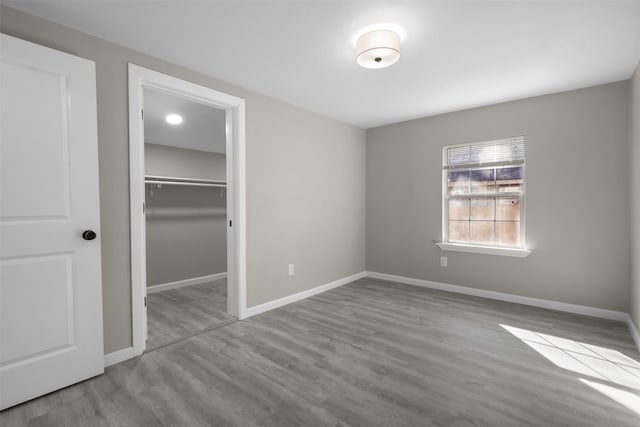 unfurnished bedroom featuring a walk in closet, light wood-type flooring, and a closet