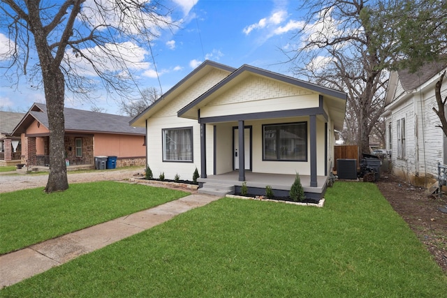 bungalow-style house featuring covered porch, cooling unit, and a front yard