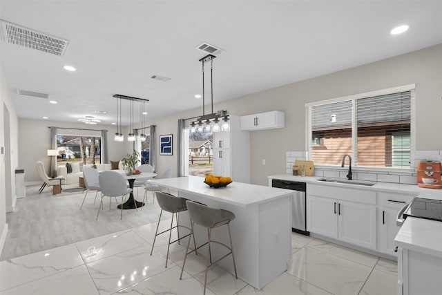 kitchen featuring sink, white cabinets, a kitchen island, decorative light fixtures, and stainless steel dishwasher