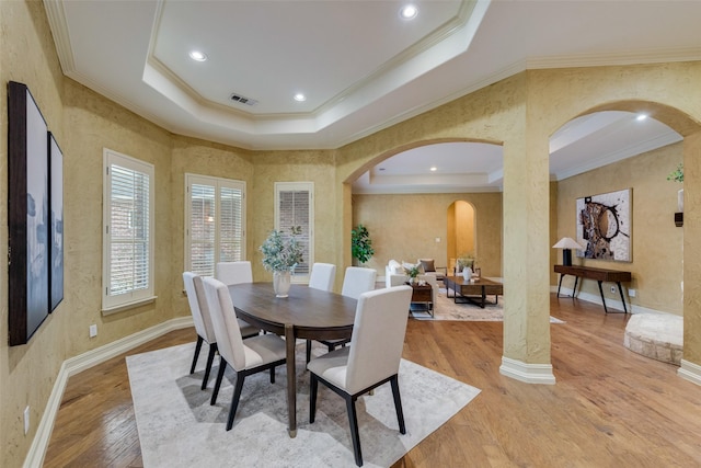 dining area with crown molding, hardwood / wood-style flooring, and a raised ceiling