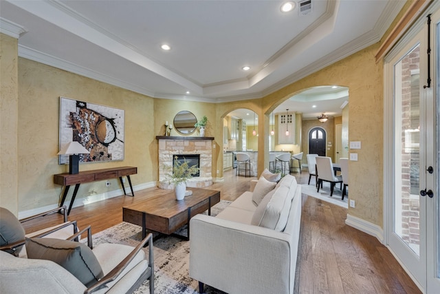 living room featuring hardwood / wood-style flooring, ornamental molding, and a raised ceiling