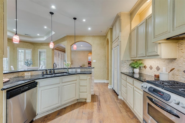 kitchen featuring stainless steel appliances, cream cabinets, sink, and decorative light fixtures